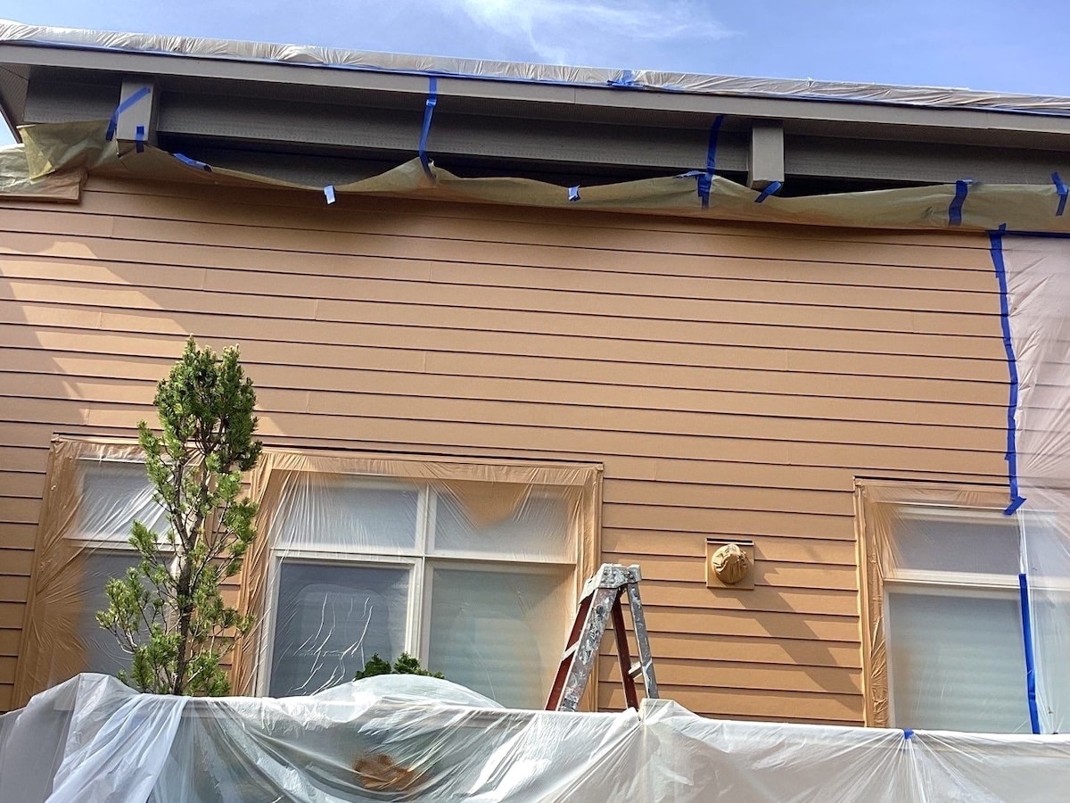 Exterior House Painting Project Underway, Complete With Painters Tape, Drip Cloths, Ladder
